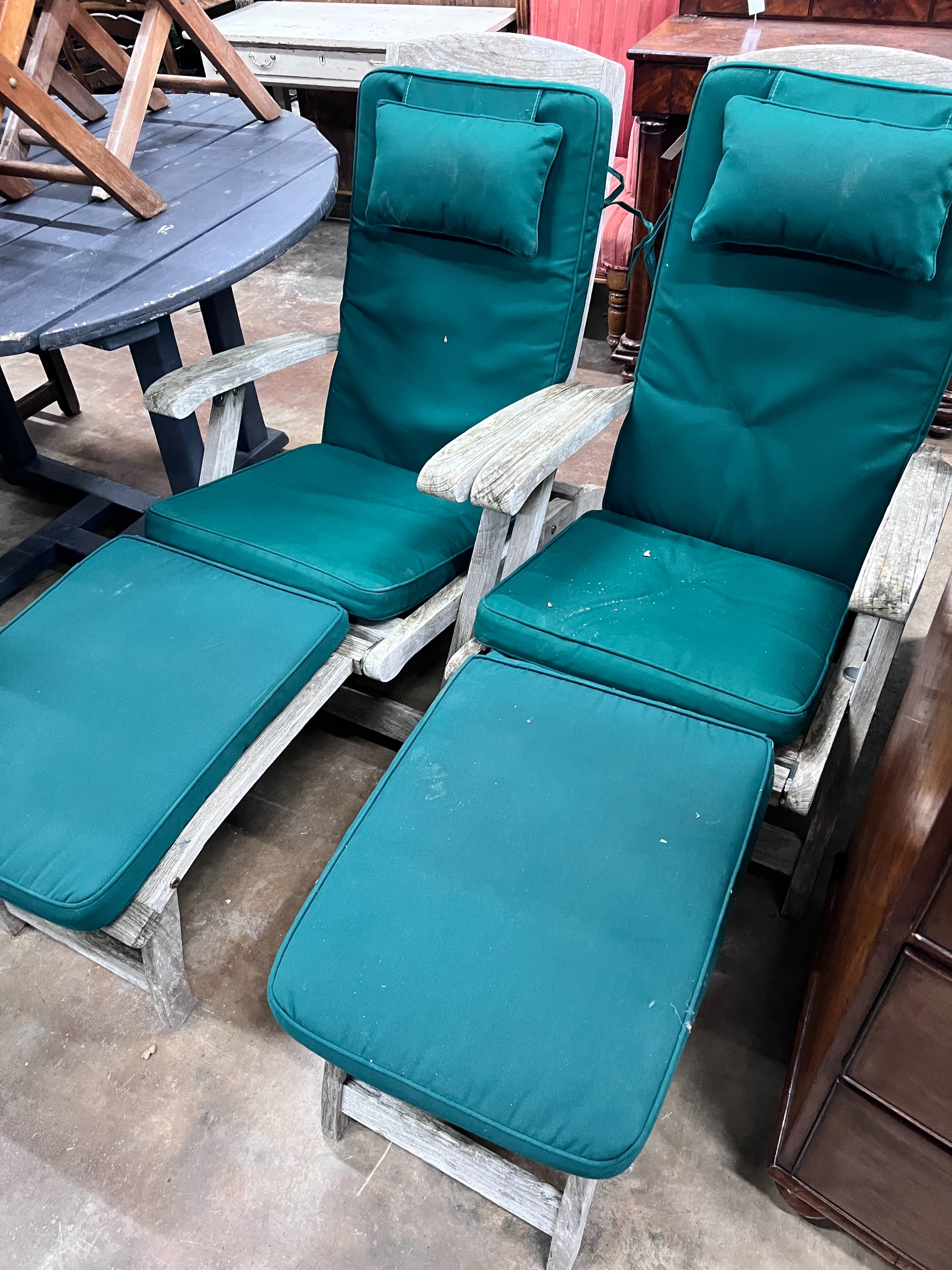 A pair of Indian Ocean weathered teak Burnham steamer chairs with green fabric squab cushions *Please note the sale commences at 9am.